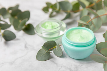 Jar of moisturizing cosmetic cream for face, hands and body with eucalyptus leaves on marble background. Natural organic product. Beauty and spa concept. Body care. Space for text.Copy space.