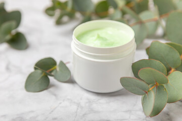 Obraz na płótnie Canvas Jar of moisturizing cosmetic cream for face, hands and body with eucalyptus leaves on marble background. Natural organic product. Beauty and spa concept. Body care. Space for text.Copy space.