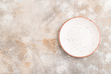 Empty white ceramic plate on brown concrete background. Top view, copy space