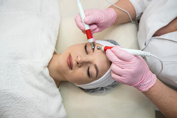 Cosmetologist makes hardware procedure for smoothing wrinkles on female face at spa
