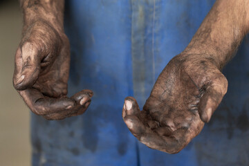 Dirty hands of a young man in blue overalls, auto mechanic, close-up.