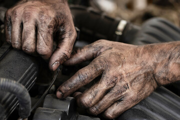 Dirty male hands close-up. A man repairs a car engine in a garage.