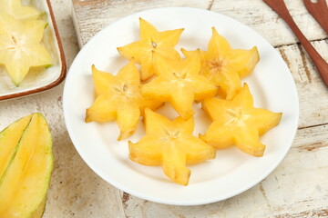 Sliced fresh organic star fruit served in white plate on white background