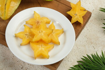 Sliced fresh organic star fruit served in white plate on white background