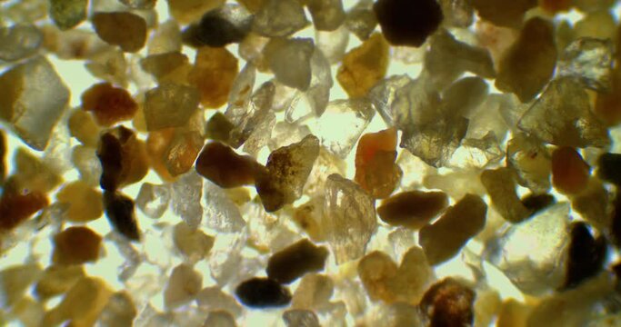 Grains of sand under a microscope. Small rocks under a scope. Tiny crystals under magnification zoom. Glass under a microscope. Cinematic beach sample