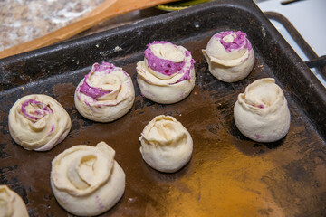 Buns with jam lie on a baking sheet.