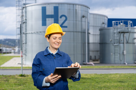 Female engineer with tablet computer on a background of Hydrogen factory - Powered by Adobe