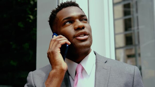 Happy Black, African American Businessman talking on smartphone outdoors, urban street