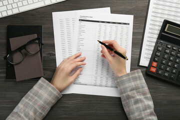 Woman working with accounting documents at wooden table, top view