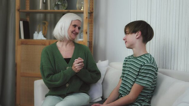 Grandson kid hugging grandmother at home. Happy Family with smiling face. Grandparents and grandchildren love. Happy grandchild boy converse to grandma surprised hugging cuddling enjoying embrace 