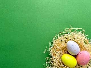 Happy Easter postcard. Multicolored Easter eggs in a nest on a green background, image with selective focus, top view