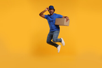 Fototapeta na wymiar Happy courier with parcel jumping on orange background