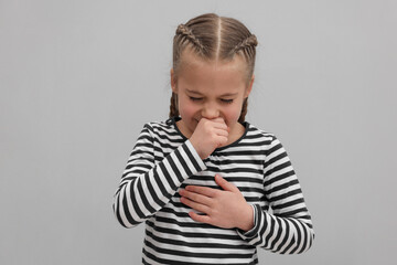 Sick girl coughing on gray background. Cold symptoms