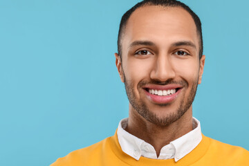 Smiling man with healthy clean teeth on light blue background. Space for text