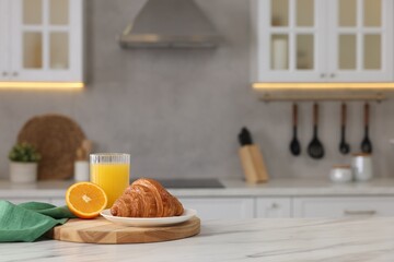 Fototapeta na wymiar Breakfast served in kitchen. Fresh croissant and orange juice on white table. Space for text