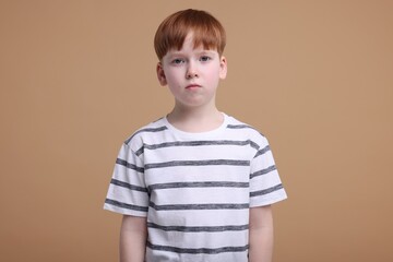 Portrait of sad little boy on beige background