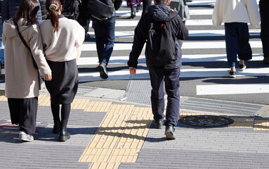 冬の昼の街の交差点の横断歩道を渡る人々の姿