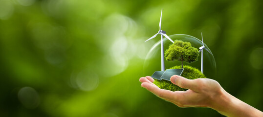 Business hand holds green globe with tree, wind turbine and solar powered for ESG, CO2 and Net Zero concept for sustainable corporate environmental development. Save the environment.