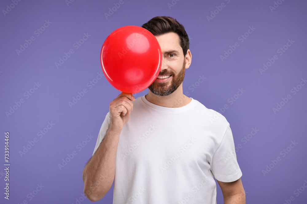 Canvas Prints Man inflating red balloon on purple background