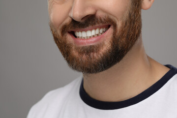 Obraz premium Smiling man with healthy clean teeth on grey background, closeup