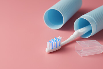 Toothbrush in a travel case on a pink background from a low angle view.