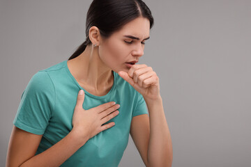 Woman coughing on grey background, space for text. Cold symptoms