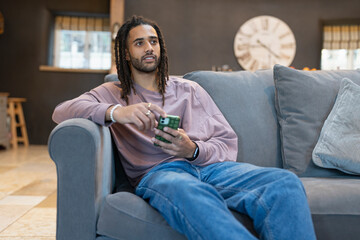 Obraz premium Man with dreads relaxing on sofa and using phone