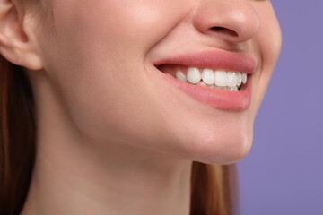 Woman with clean teeth smiling on violet background, closeup