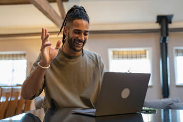 Man with dreads talking on video call on laptop at home