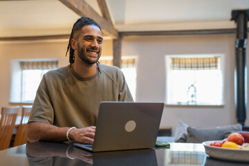 Man with dreads working on laptop at home