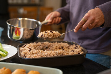 Man holds spoon with rice and black beans