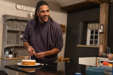 Smiling man placing candles on birthday cake  - obrazy, fototapety, plakaty