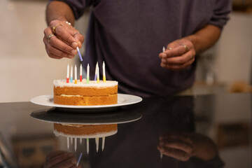 Man placing candles on birthday cake 