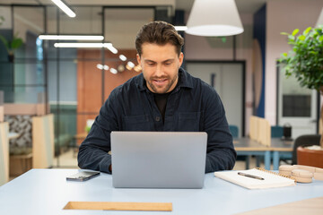 Smiling businessman working on laptop in office