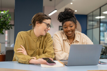 Smiling businesswomen working together on laptop in office