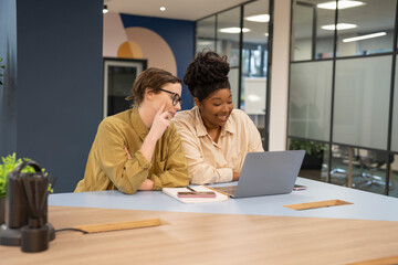 Smiling businesswomen working together on laptop in office