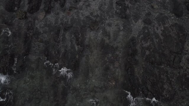 Overhead drone shot of ocean with rocks and waves, with moving down camera angle, 2024 Japan local