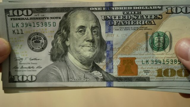 large number of dollars on a table. Dollars close up. Young man counts cash money dollars. Income, winner and Business concept. Many US dollars lie down, fly, rush to the table. A stack of $ 100 bills