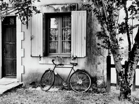 Black and white photo of a French house with old rusty bicycle outside
