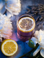 Lavender cocktail with gin or lemonade on a blue table with white peonies