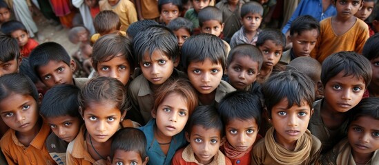 Image of impoverished children gazing at the camera with solemn expressions. - obrazy, fototapety, plakaty