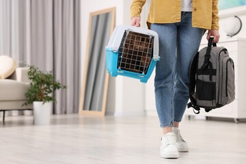 Travel with pet. Woman holding carrier with dog and backpack at home, closeup. Space for text
