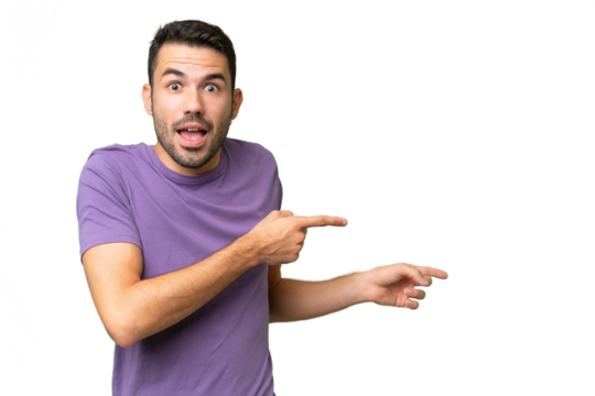 Young handsome caucasian man over isolated background surprised and pointing side