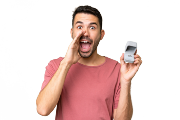Young handsome caucasian man holding a engagement ring over isolated background shouting with mouth wide open