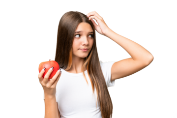 Teenager caucasian girl holding an apple over isolated background having doubts and with confuse face expression