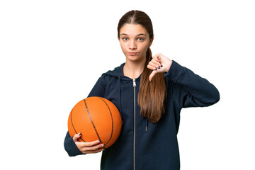 Teenager caucasian girl playing basketball over isolated background showing thumb down with negative expression