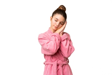 Teenager girl in a bathrobe over isolated chroma key background making sleep gesture in dorable expression