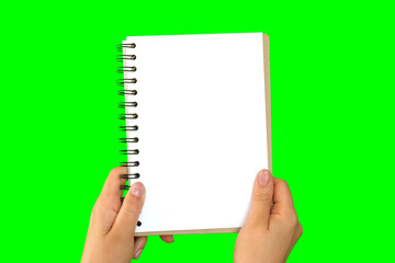 Female Hand Holding Notepad with blank Page Isolated On Green Background. Close Up. Chroma Key Screen. Woman's Hand with Empty Card Paper MockUp. Advertisement gesture. Notebook Mock Up. Greenscreen