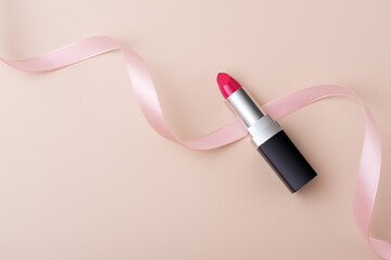 Pink lipstick in black and metal tube packaging with pink decorated ribbon