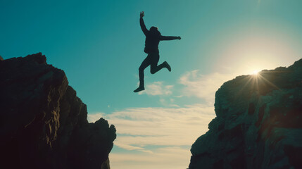 Silhouette of Enthusiastic man jumping between two cliffs in success and freedom concept
